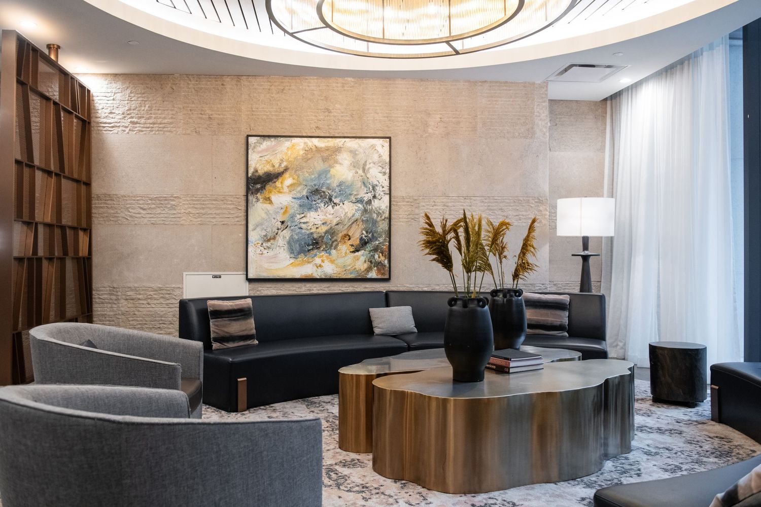 Elegant sitting area featuring abstract wall art, dark sofa, and round wooden coffee table.