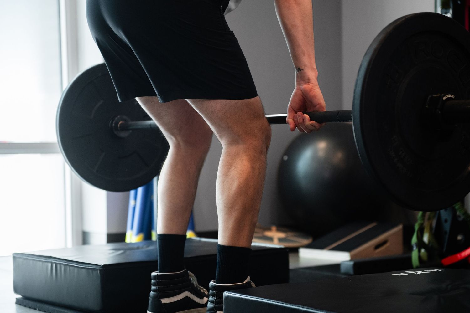 Person performing weightlifting exercise with proper form on gym platform.