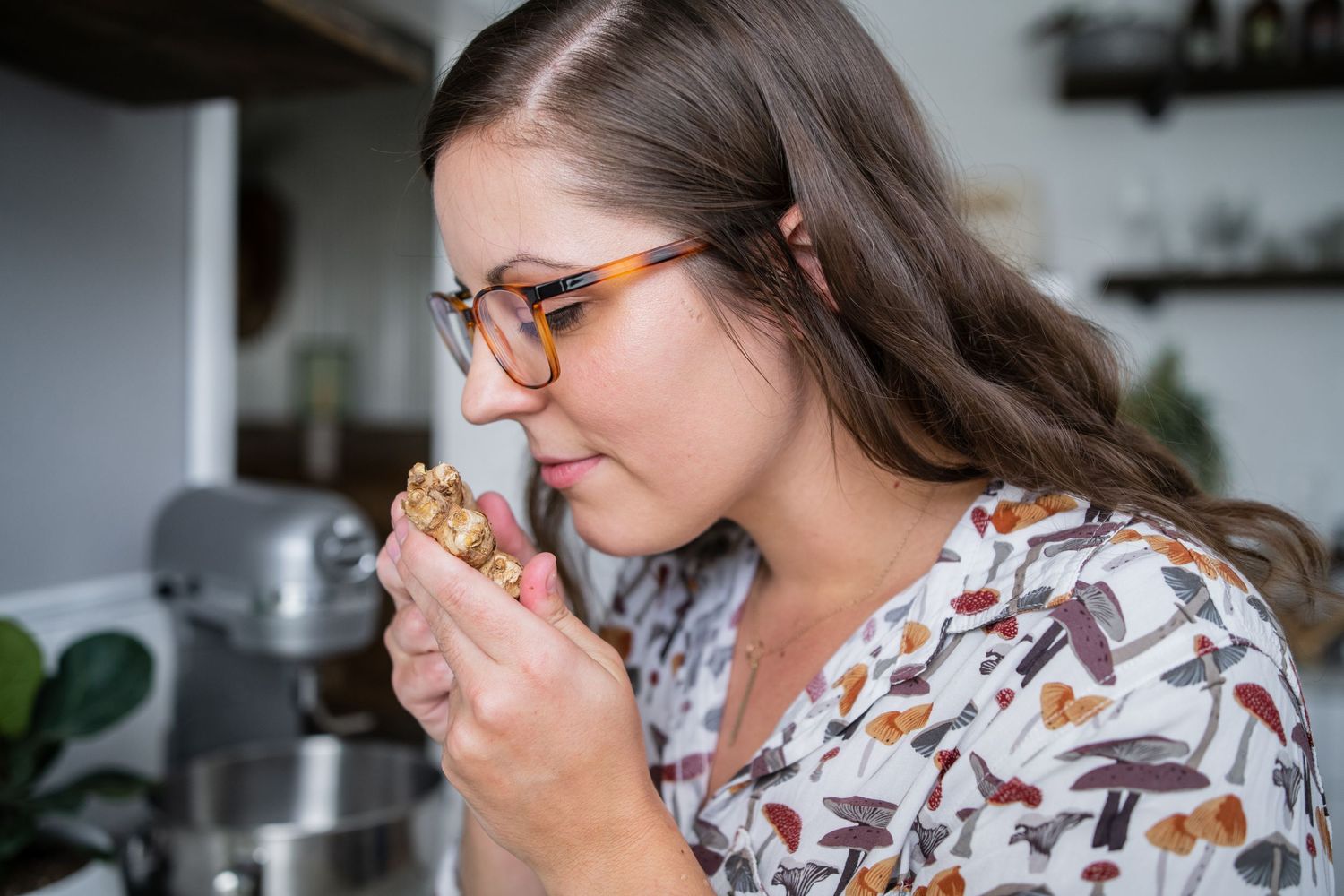 Someone tasting food while cooking in a kitchen with decorative open shelving.