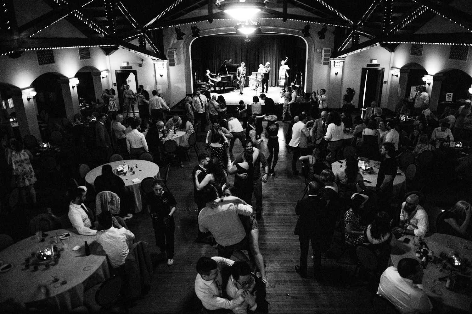 A black and white overhead view of a crowded wedding reception with couples dancing.