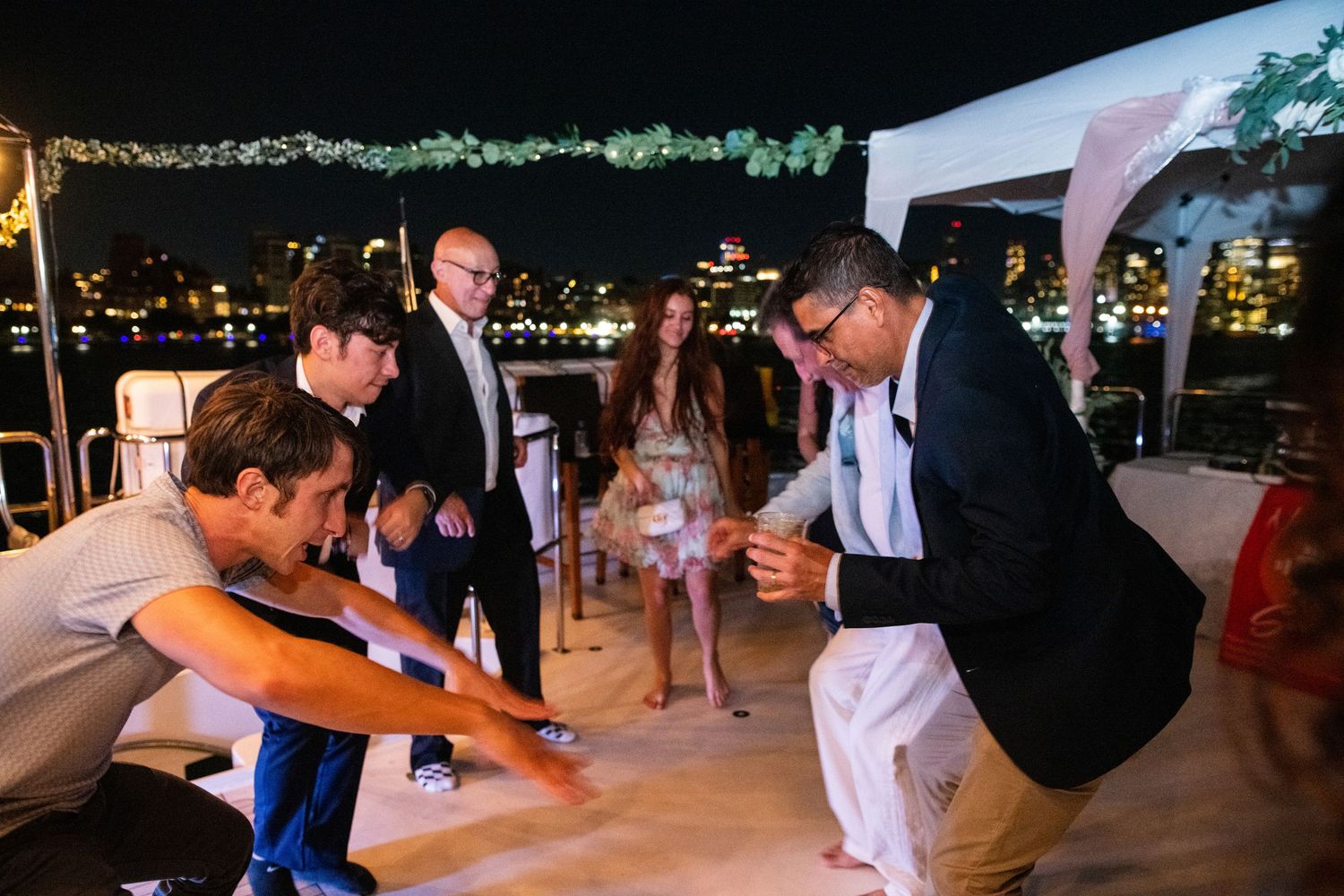 Wedding guests dancing and having fun on an outdoor dance floor with string lights overhead.
