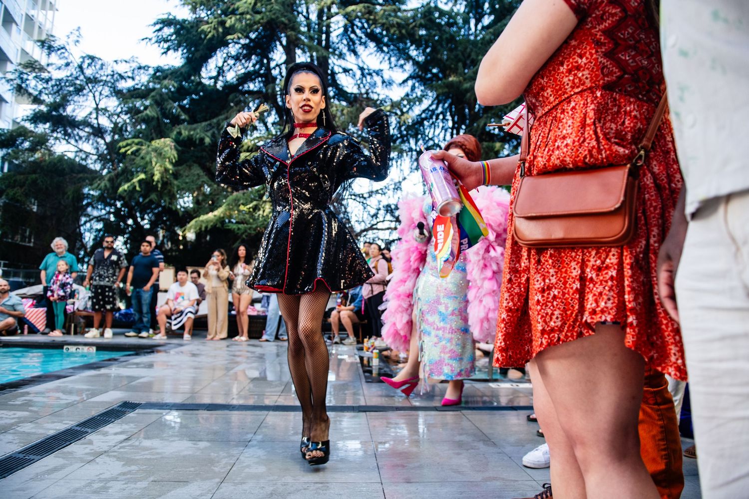 Fashion show at a poolside party with models walking in stylish dresses.