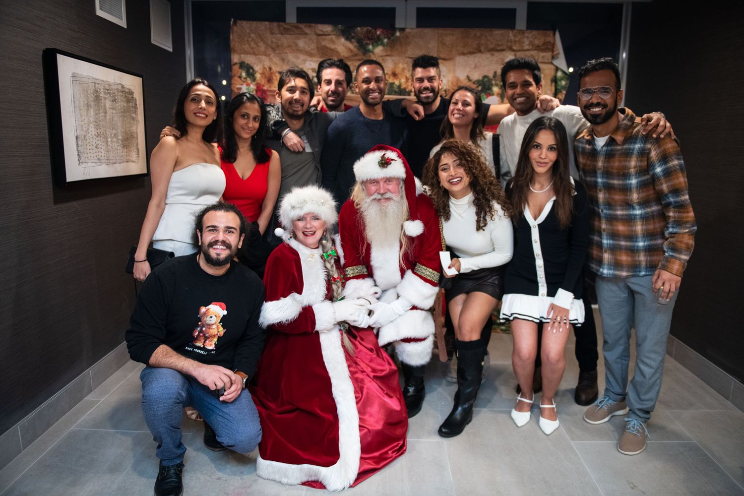 A festive holiday gathering with Santa and Mrs. Claus surrounded by guests in formal attire.