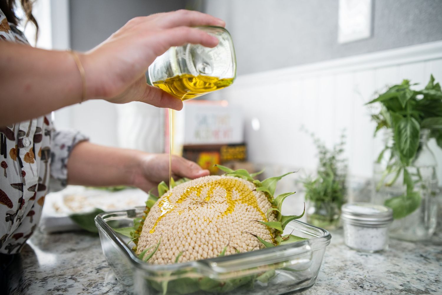Pouring oil over a large yellow melon in a glass baking dish.