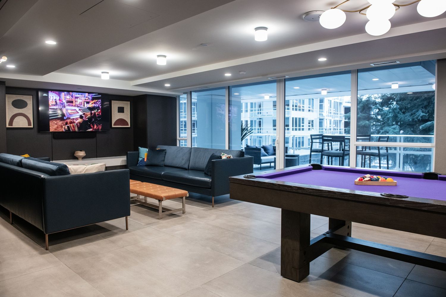 Luxury game room featuring pool table, flat screen TV, and modern seating with city views.