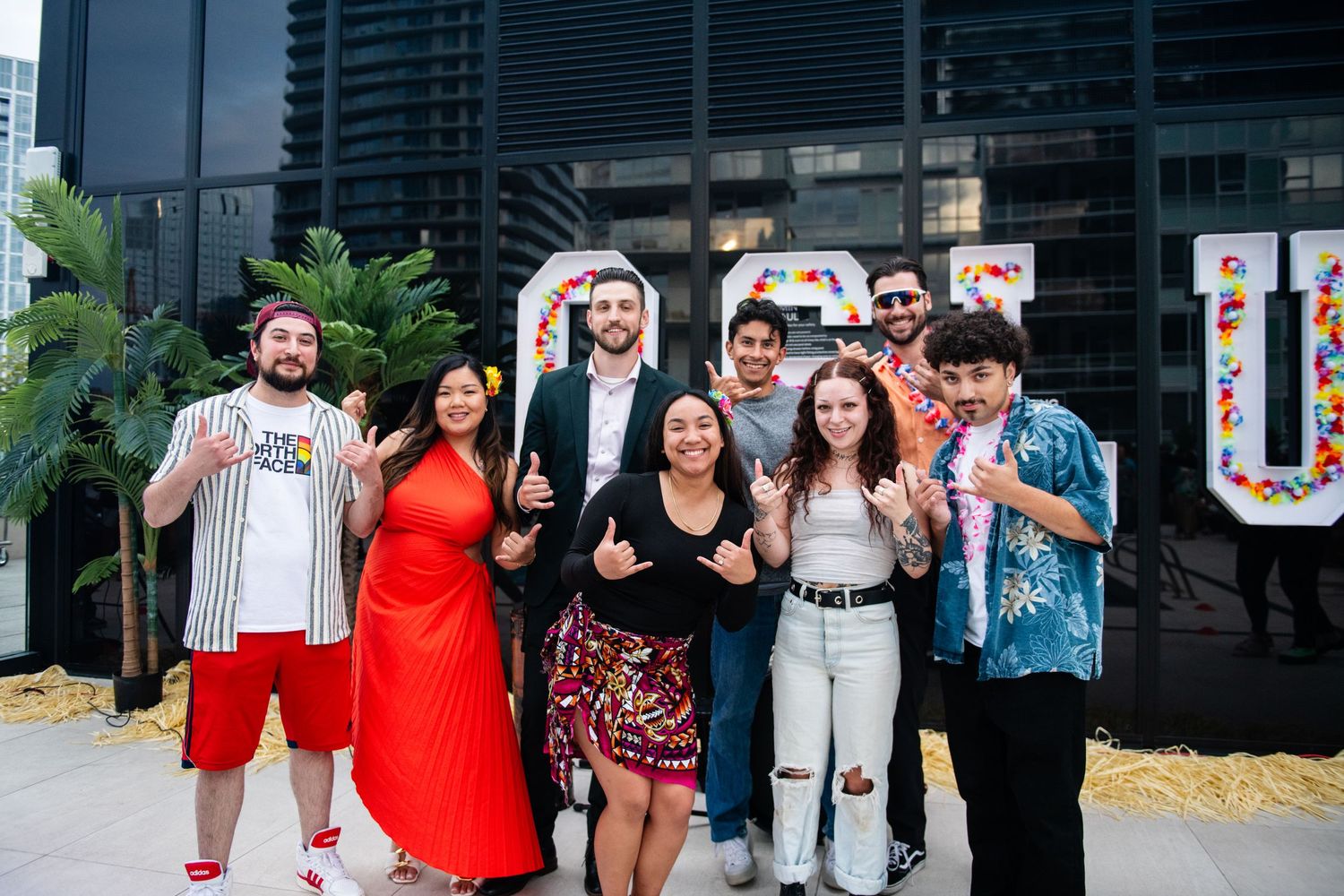 Group of friends posing together in front of large OSLU marquee sign outdoors.