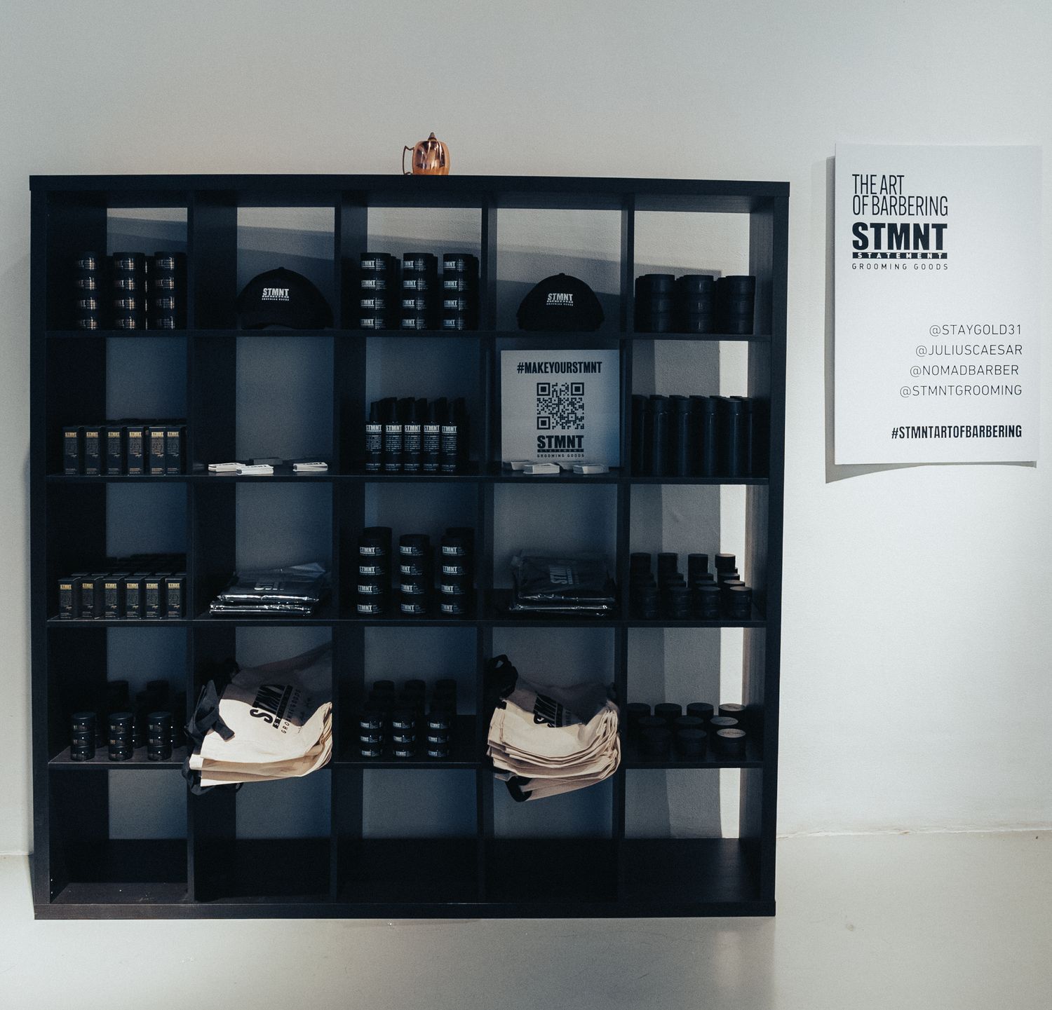 Modern black shelving unit displaying grooming products and sneakers in a retail setting.