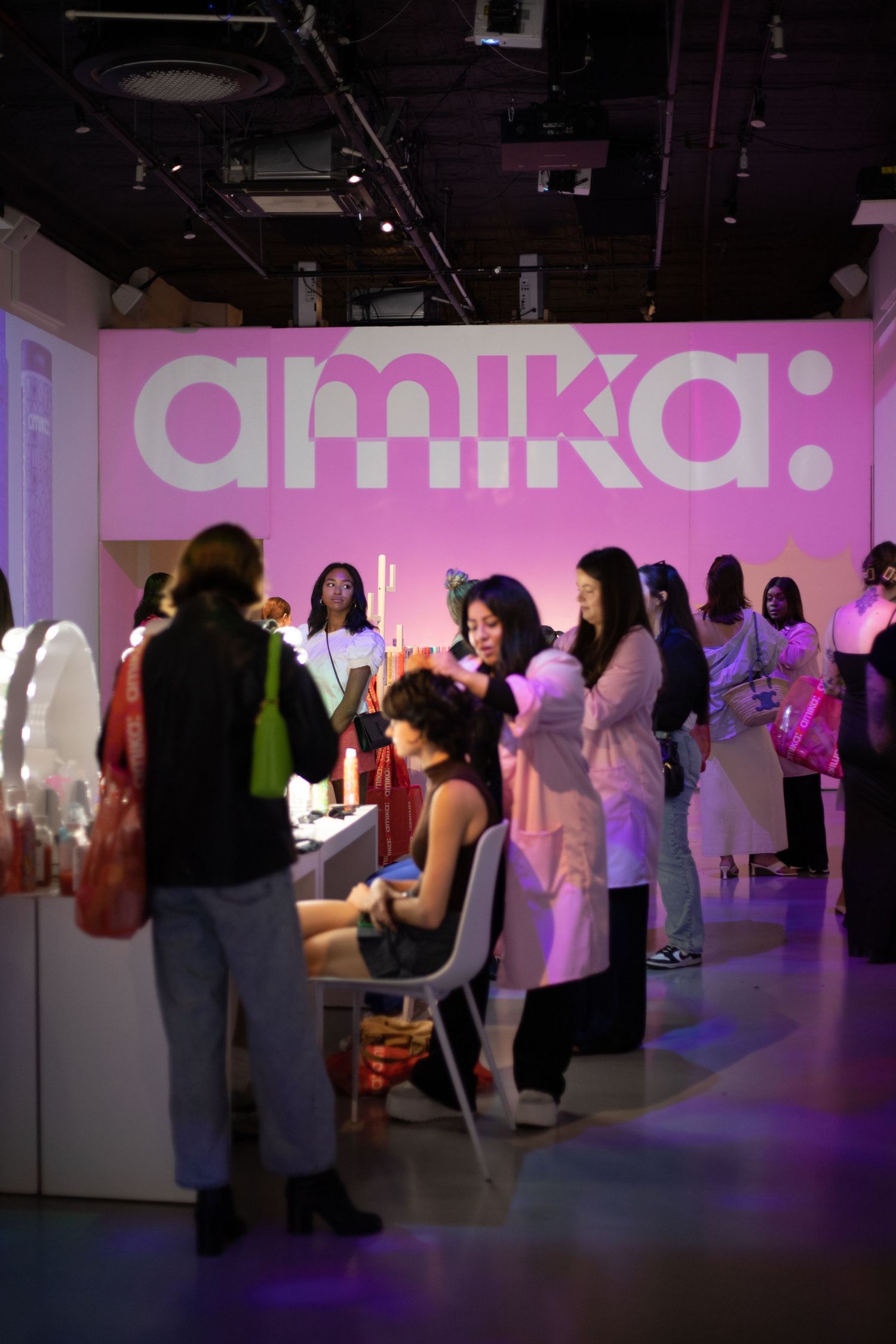 Beauty event space with pink Amika branding and people gathered for demonstrations.