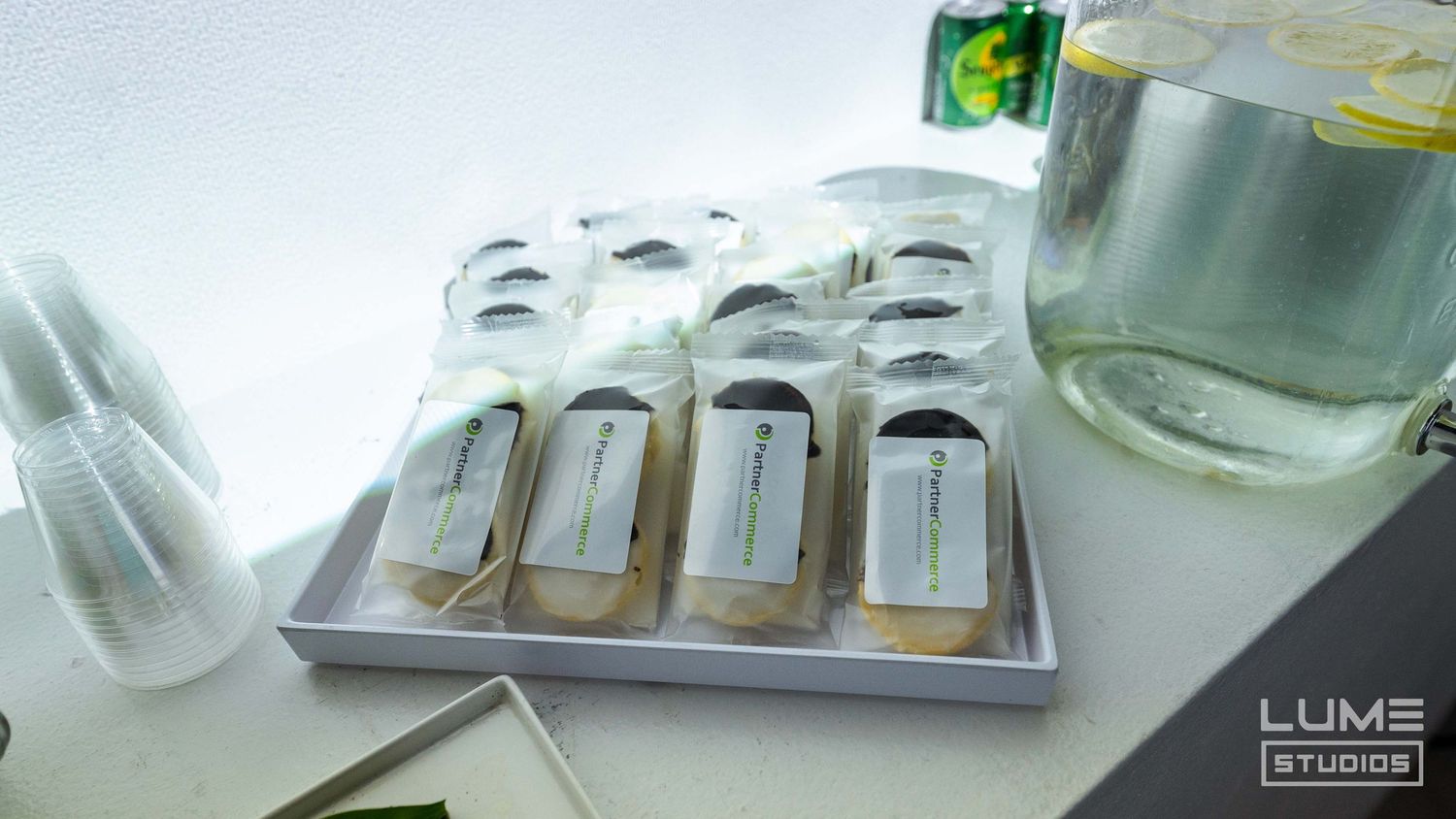 Refreshment station with bottled beverages and clear plastic cups arranged on silver tray.