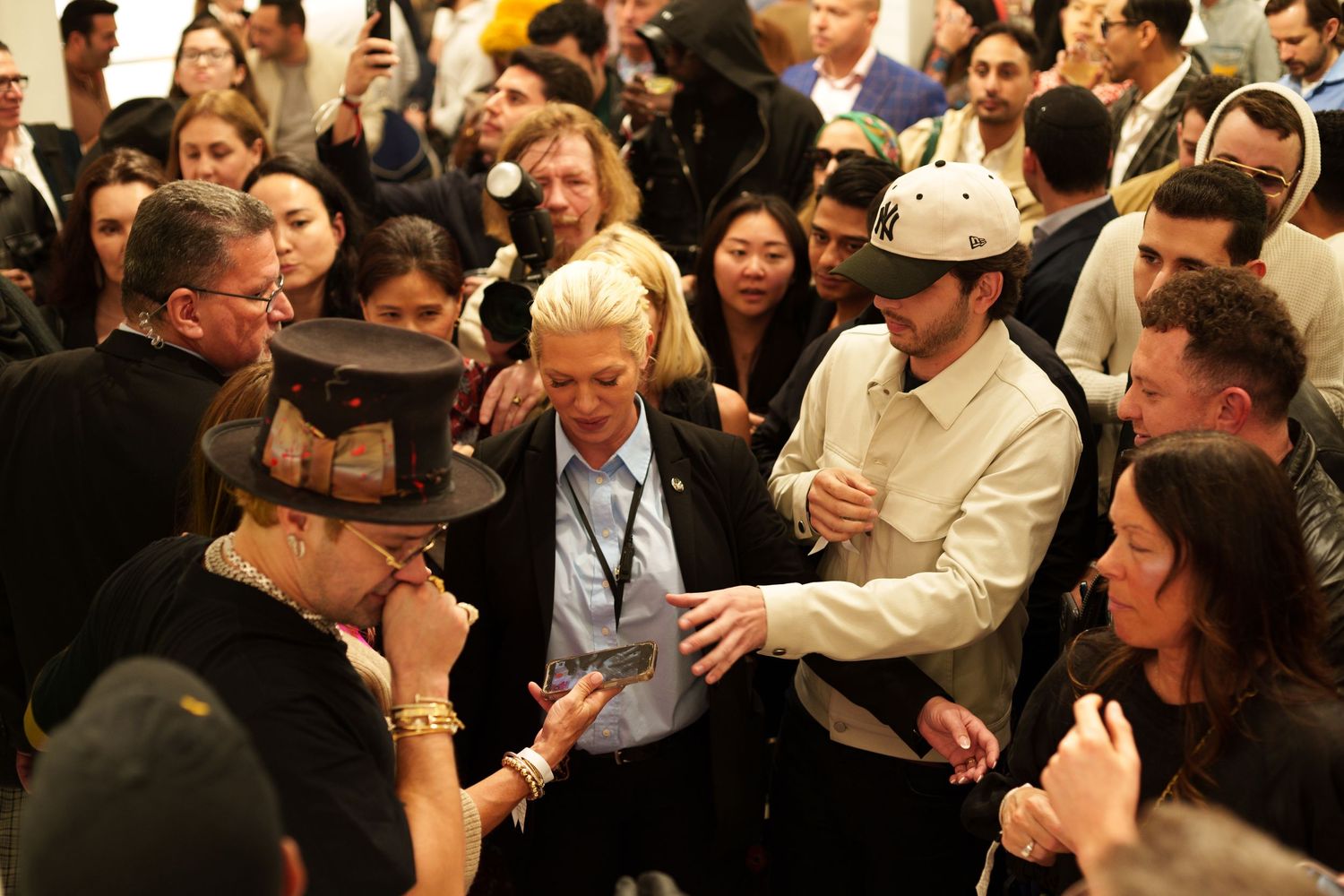 A crowd gathered around someone signing autographs at an indoor event.