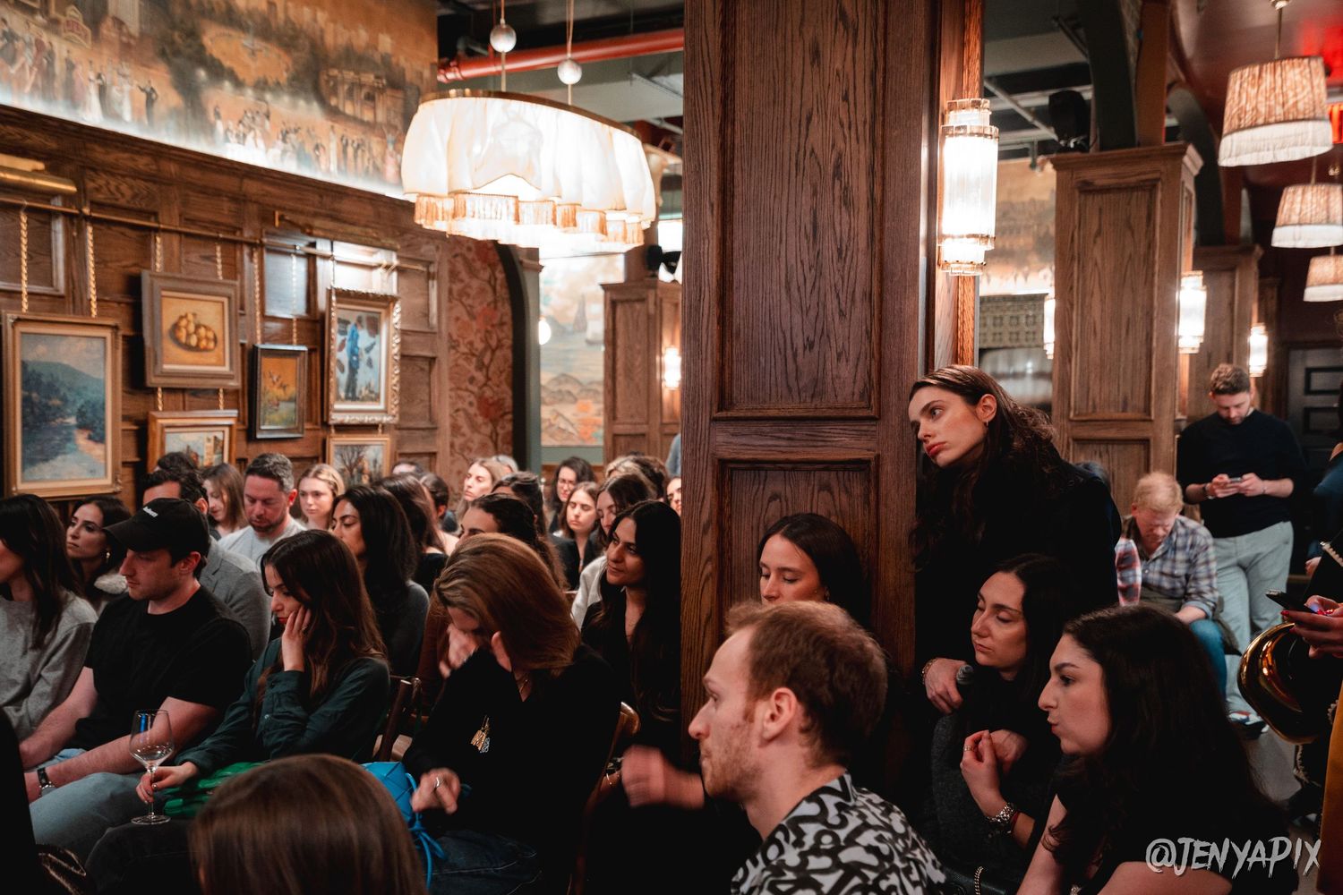 Packed pub interior with wooden decor and vintage lighting fixtures.