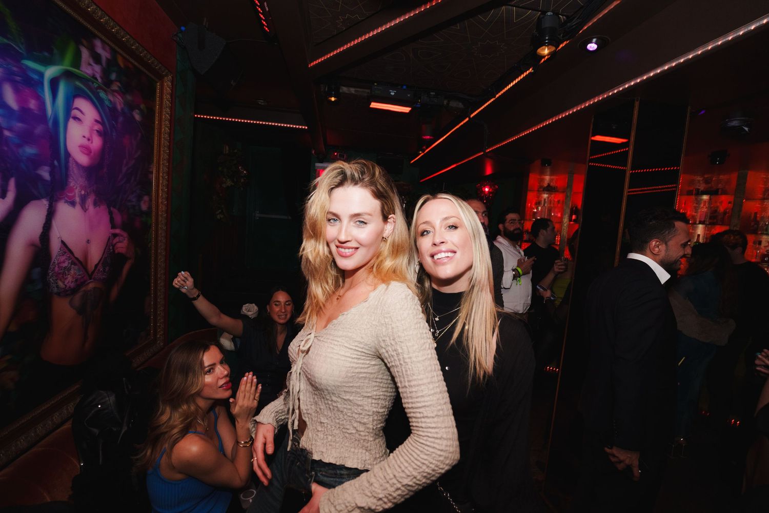 Party guests enjoying themselves at a dimly lit nightclub with purple and red lighting effects.