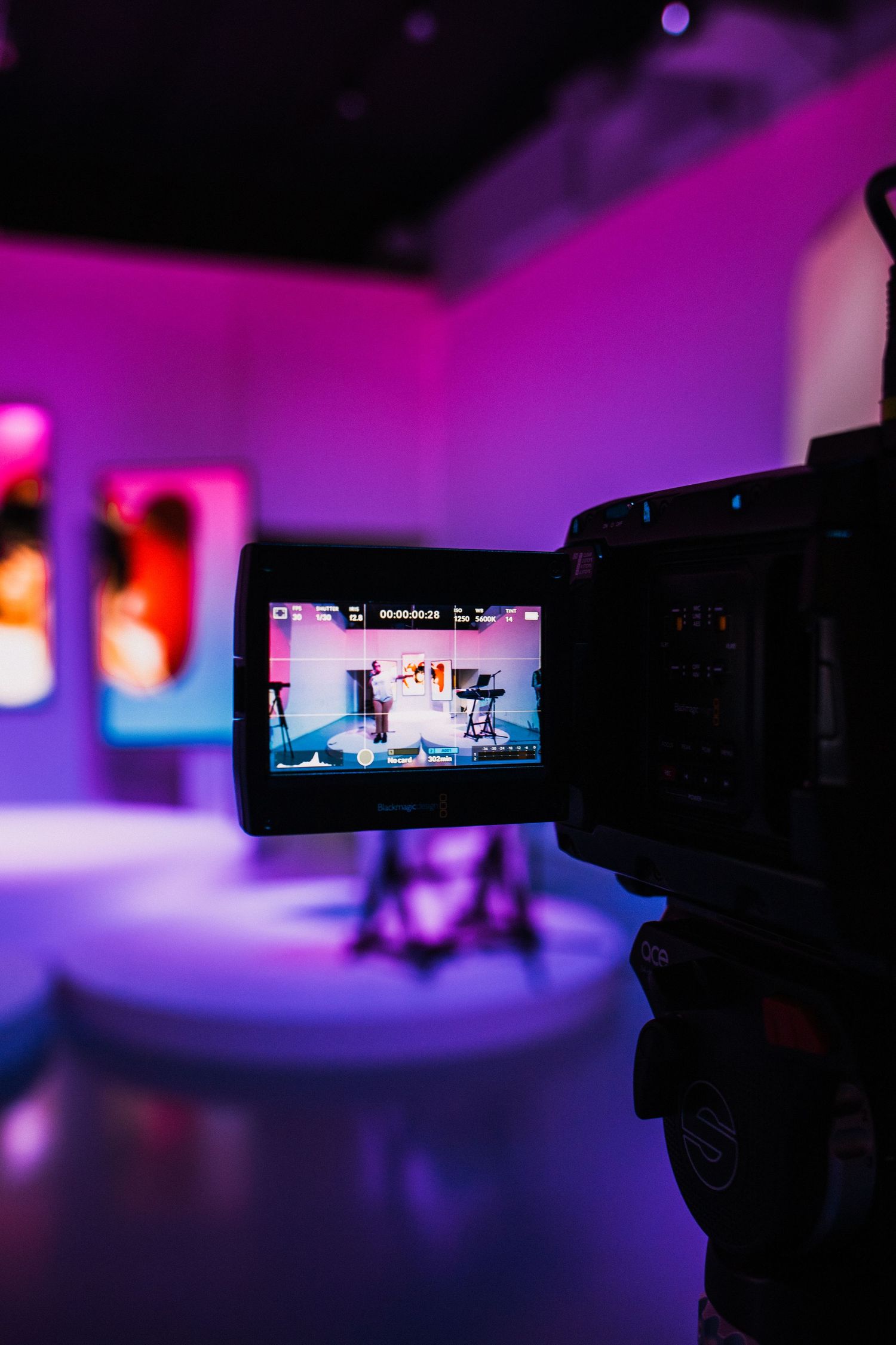 Video camera display showing studio recording with vibrant purple lighting.