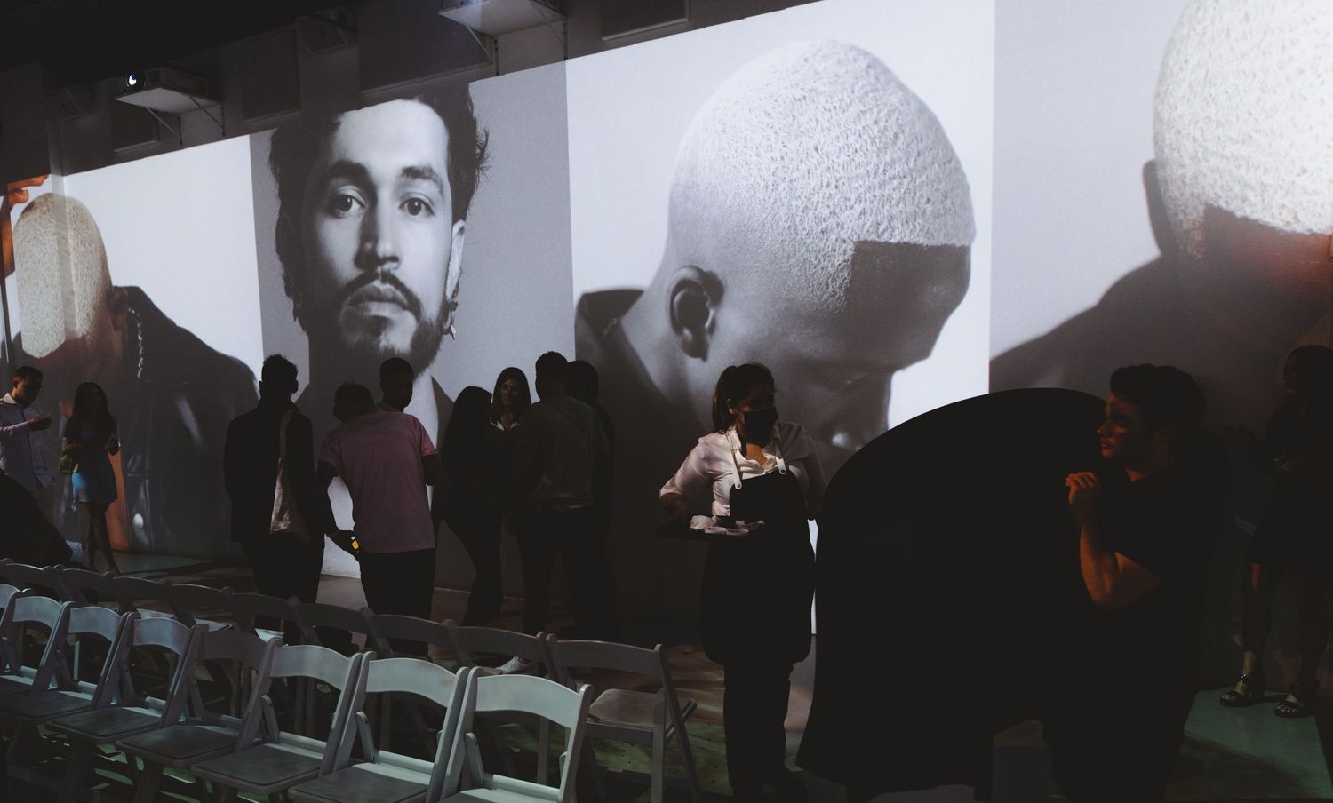 Large-scale projection display featuring portrait photography with audience silhouettes.