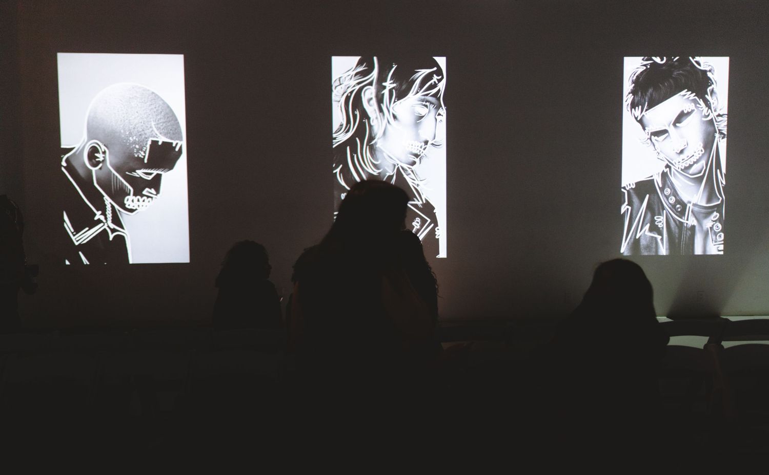 Art installation showing black and white portrait projections on gallery walls.