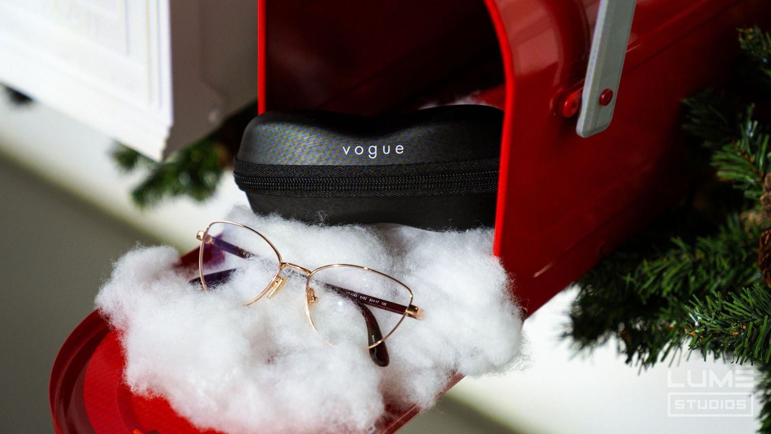 Vogue eyewear display with glasses resting on white cotton against a red backdrop.