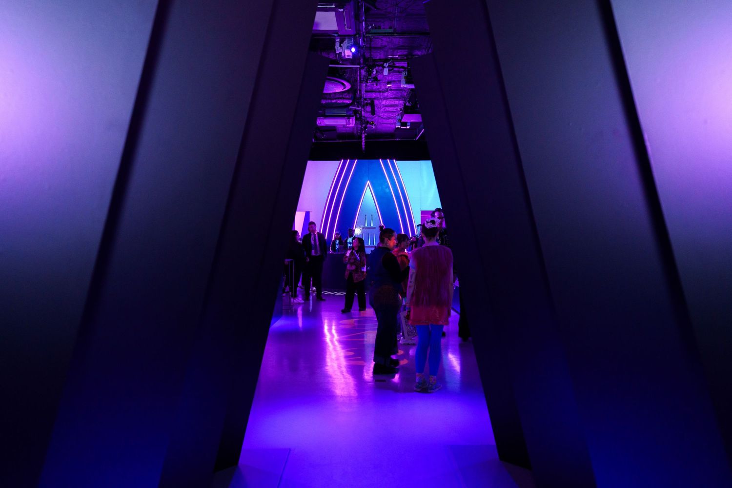 Purple-lit hallway leading to an illuminated triangle arch.