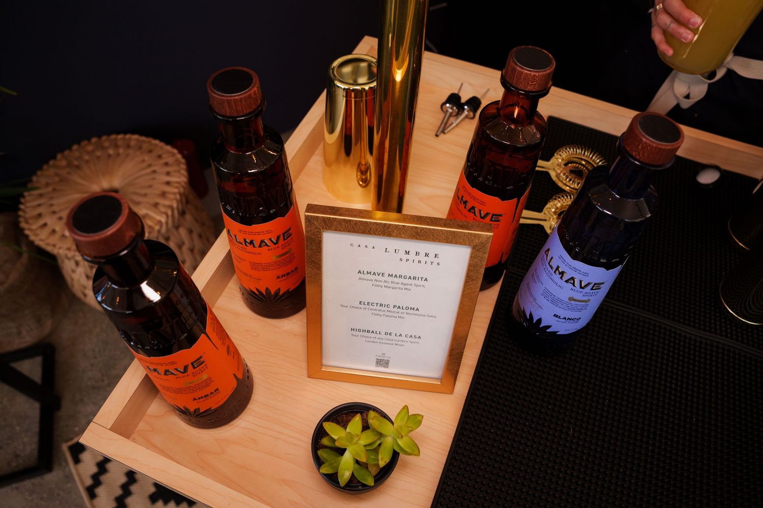 Several bottles of spirits and a succulent plant arranged on a wooden serving tray with menu card.