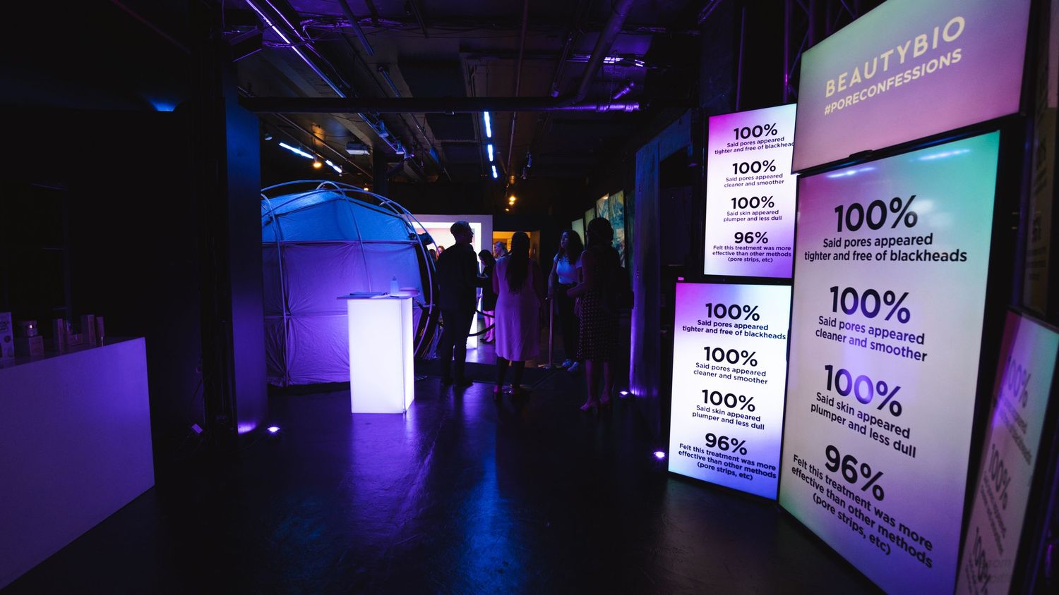 Digital displays showing product statistics in a darkened event space with purple ambient lighting.