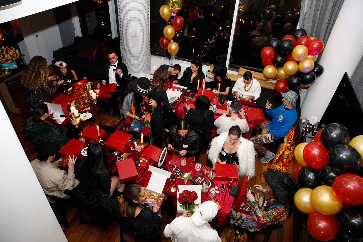 Holiday party scene with red tablecloths, gold balloons, and festive decorations.