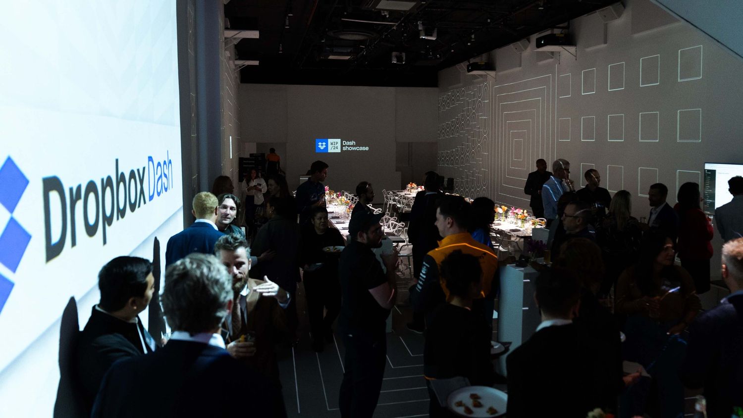 Crowded corporate event space with Dropbox logo prominently displayed.