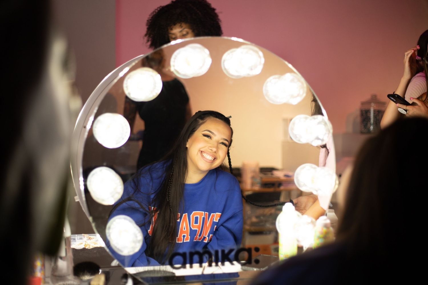 Makeup vanity mirror with bright bulbs reflecting in a backstage setting.