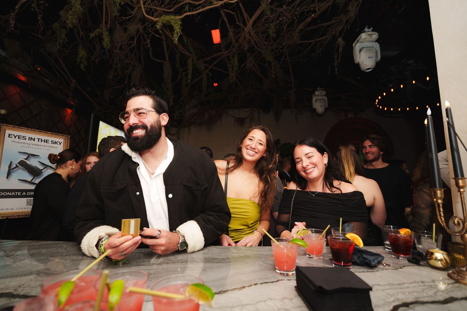 Friends enjoying colorful cocktails together at an outdoor restaurant bar.