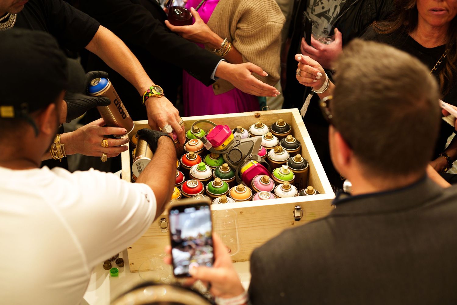 People gathered around wooden box taking photos at social event.