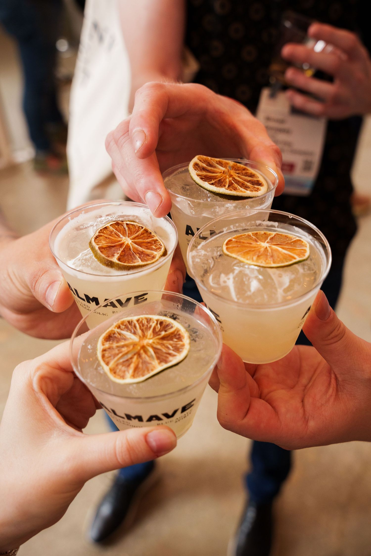 Four cocktails garnished with dried orange slices being held together in a celebratory toast.