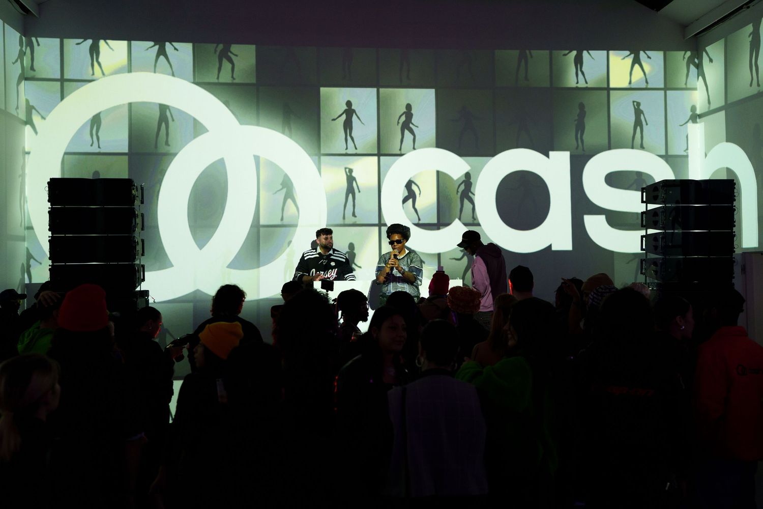 Event space with illuminated Adidas logo and crowd silhouettes against a dark background.