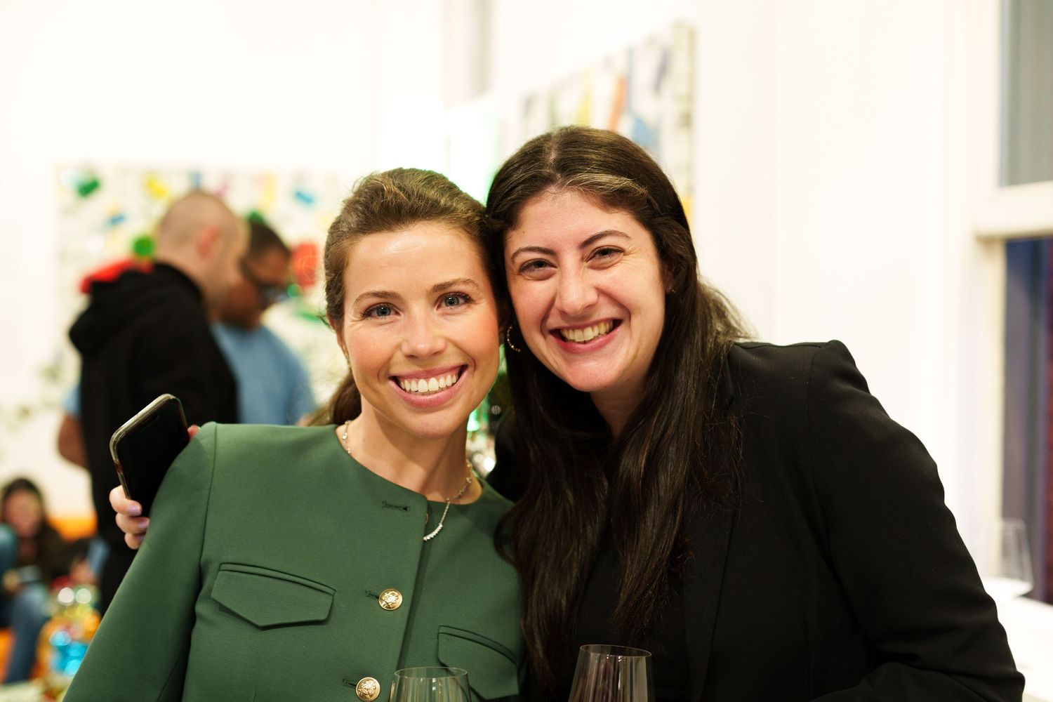Two people smiling warmly at a social event in an art gallery setting.