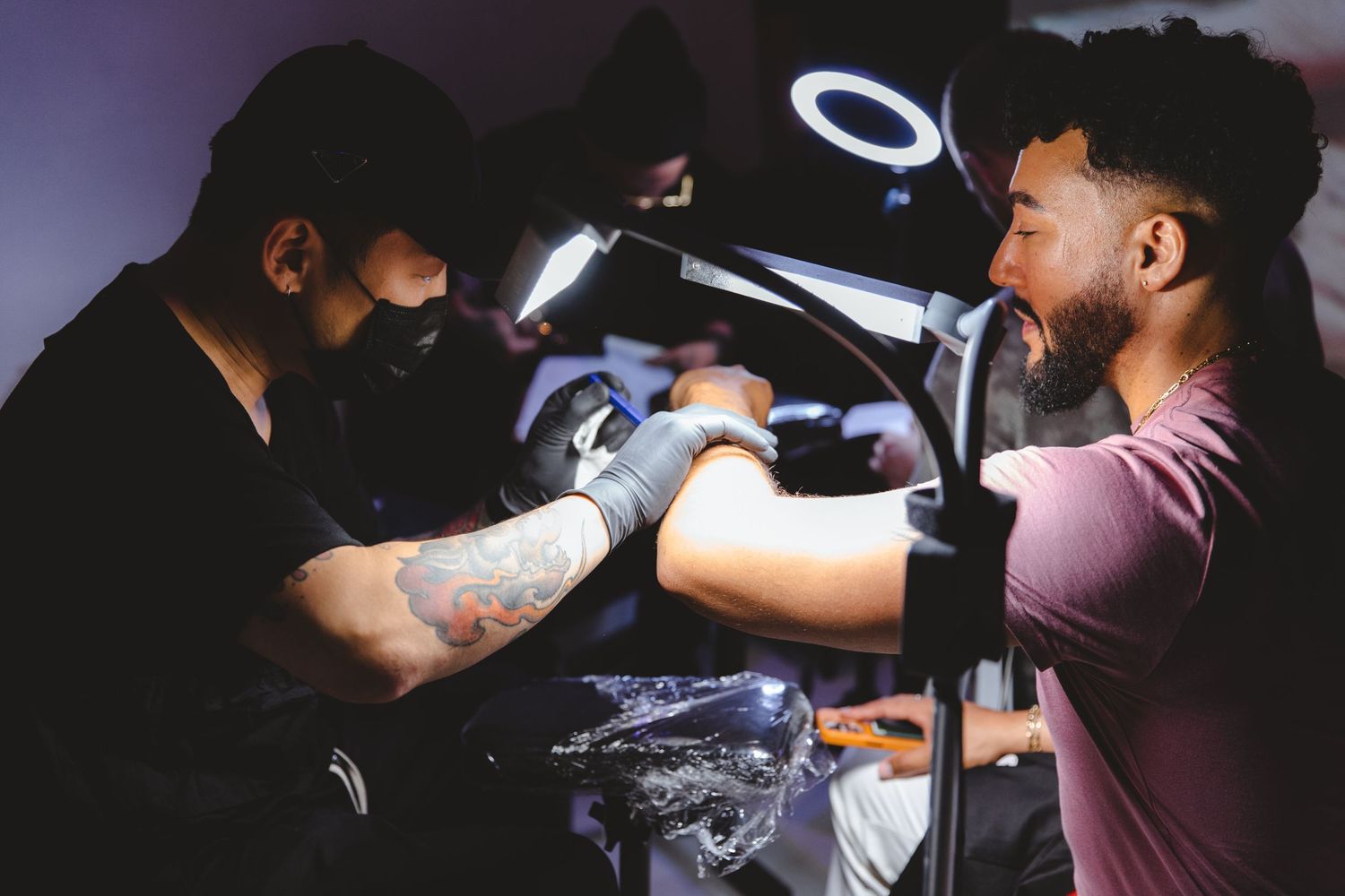 Barber performing detailed grooming work under focused lighting.