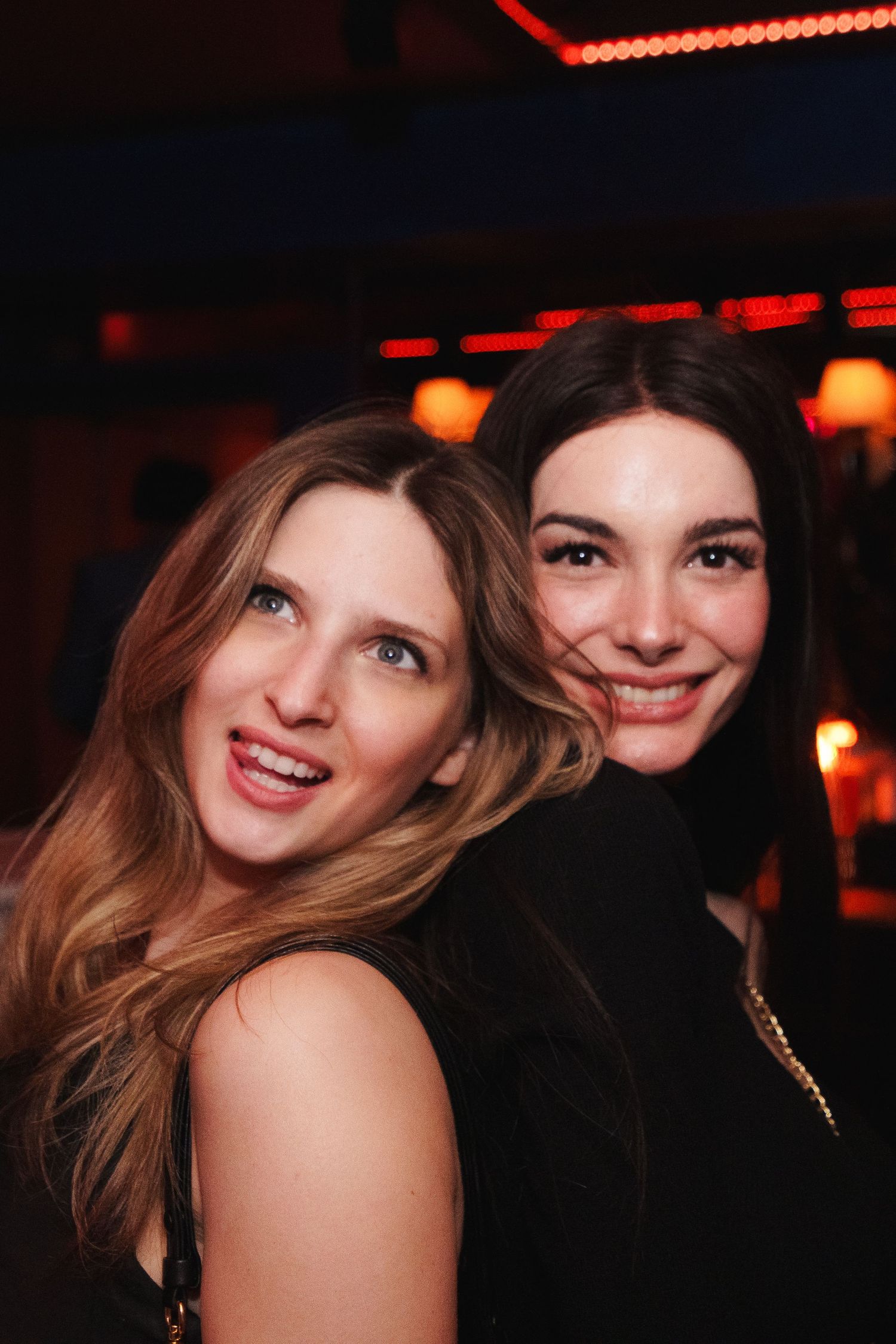 Two guests enjoying a night out at a dimly lit venue with red ambient lighting.