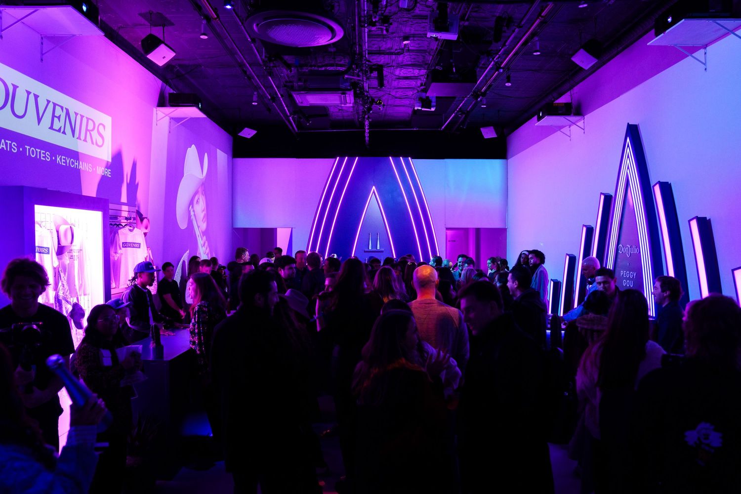 Crowded nightclub event space with geometric lighting installations.
