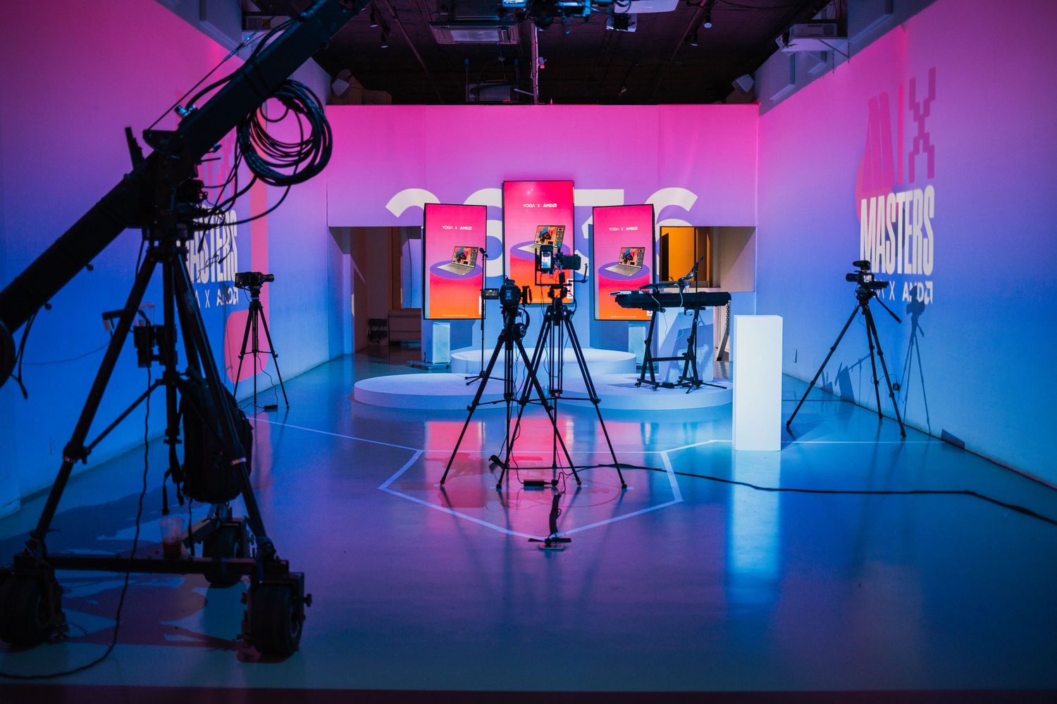 Empty studio space with professional camera equipment and dramatic pink to blue gradient lighting.