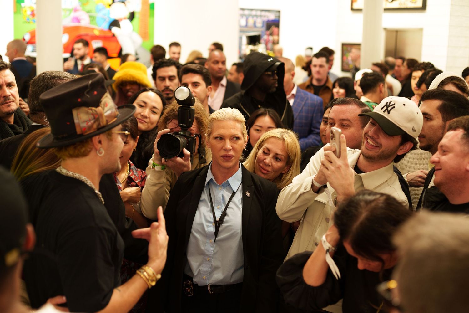 Large crowd gathered at indoor event with people taking photos.