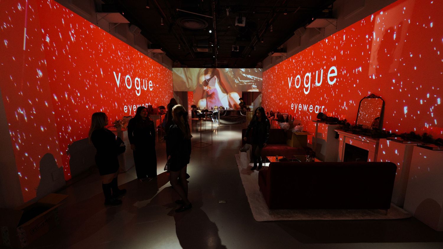 Red-lit event space with Vogue branding and dramatic projection effects.