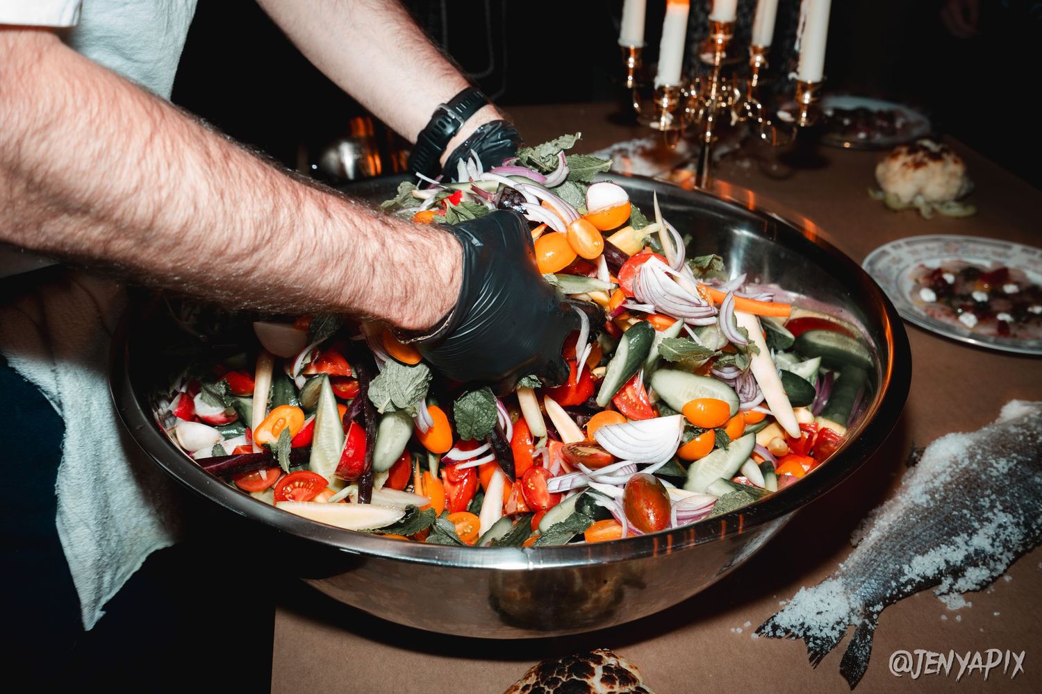 Fresh seafood and vegetables being plated on a dark serving platter.