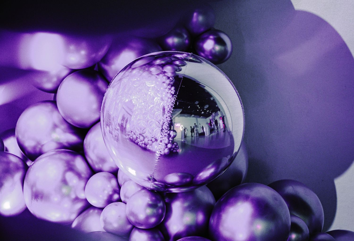 Close-up of purple metallic Christmas ornament reflecting event decorations.