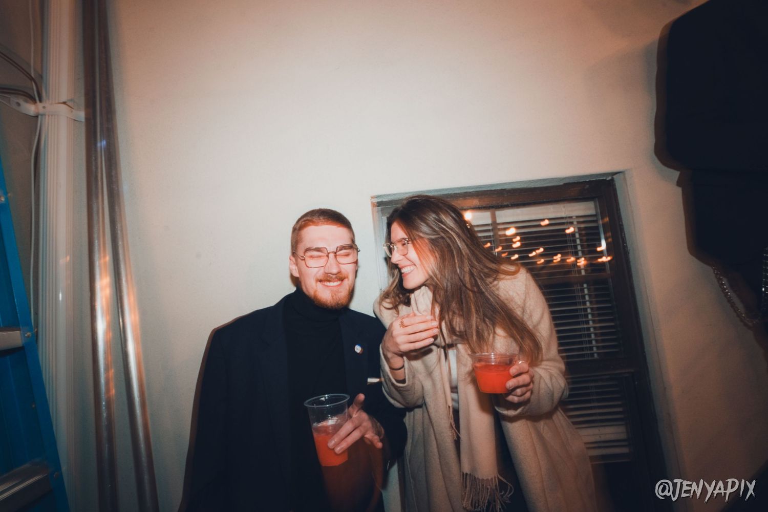 Two people socializing at an indoor party with drinks.