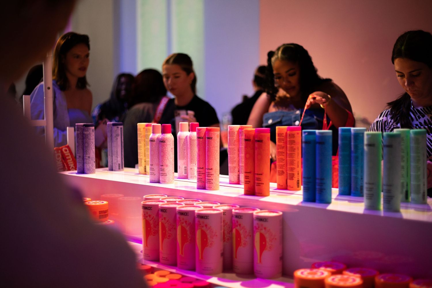 Colorful product bottles illuminated on display table at promotional event.