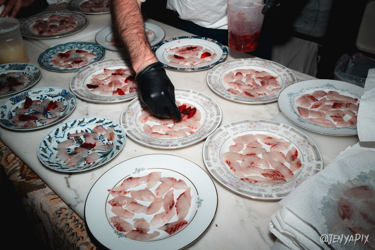 Plated dishes being arranged and garnished on white porcelain plates.