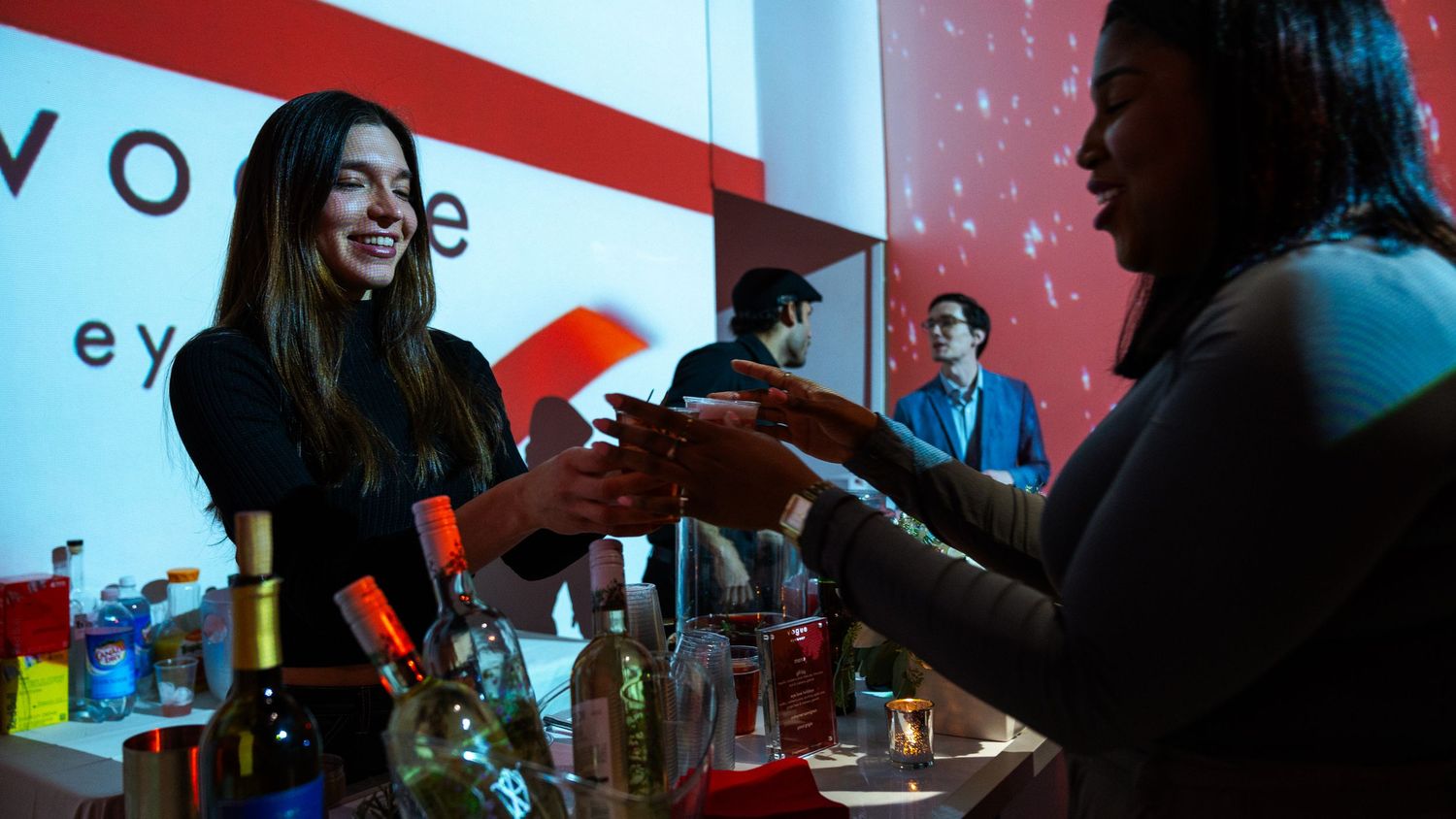 Bar service area at Vogue event with branded red wall display.