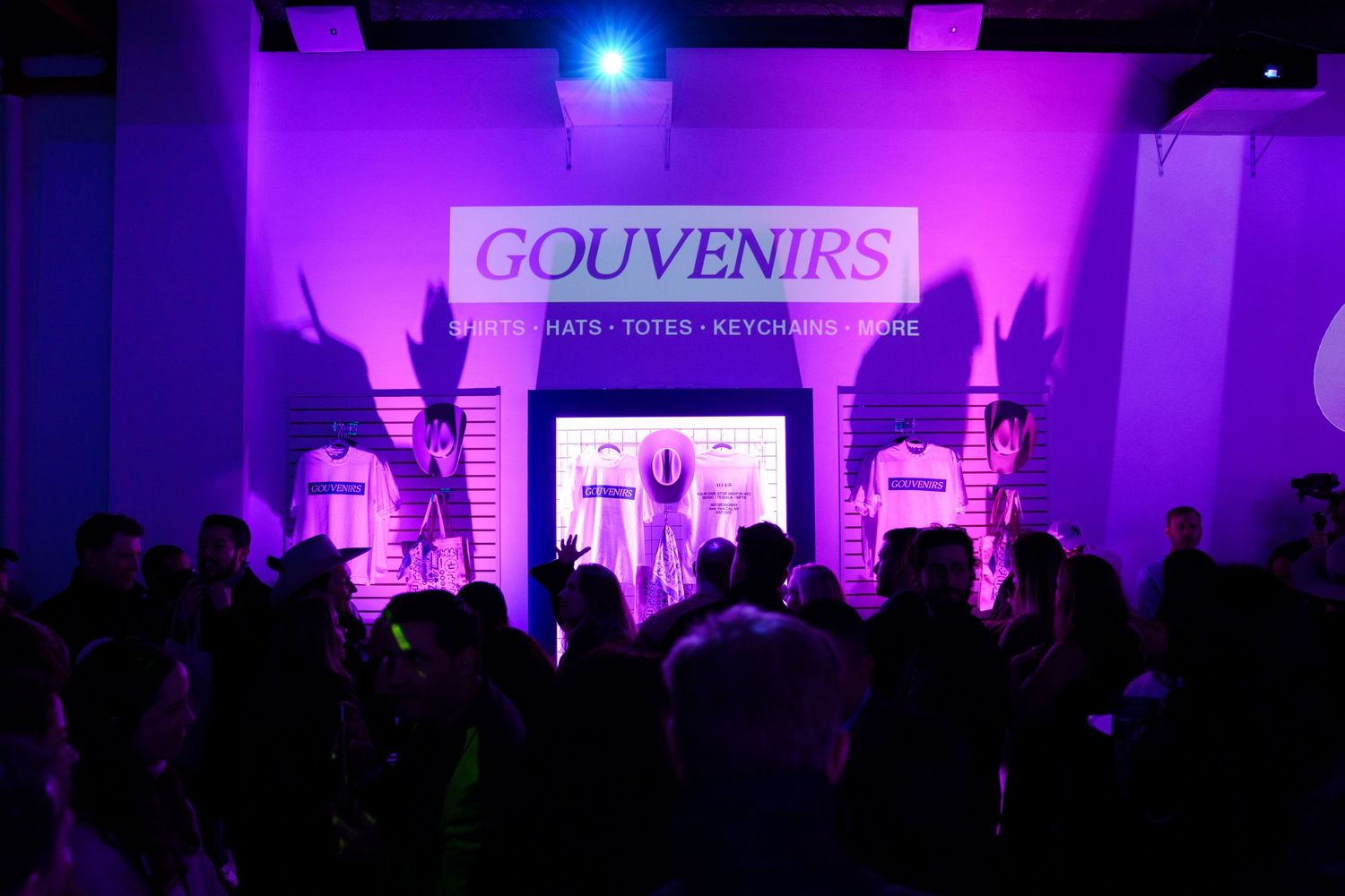 Silhouetted crowd at a Gouvenirs event with purple stage lighting.