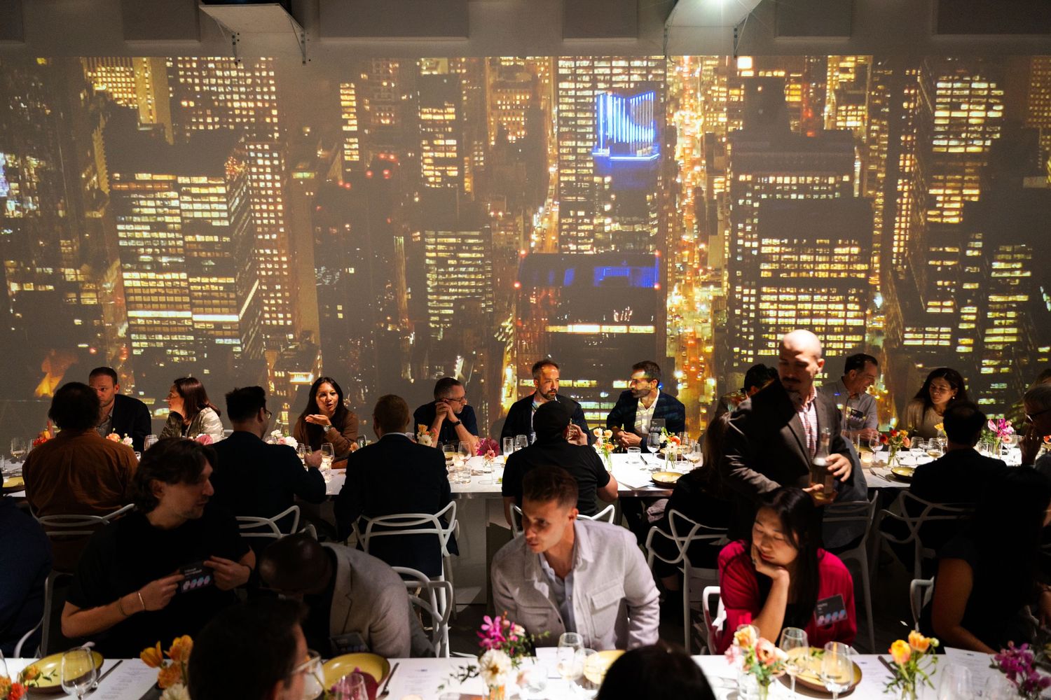 Evening corporate dinner with illuminated cityscape projections creating ambiance.