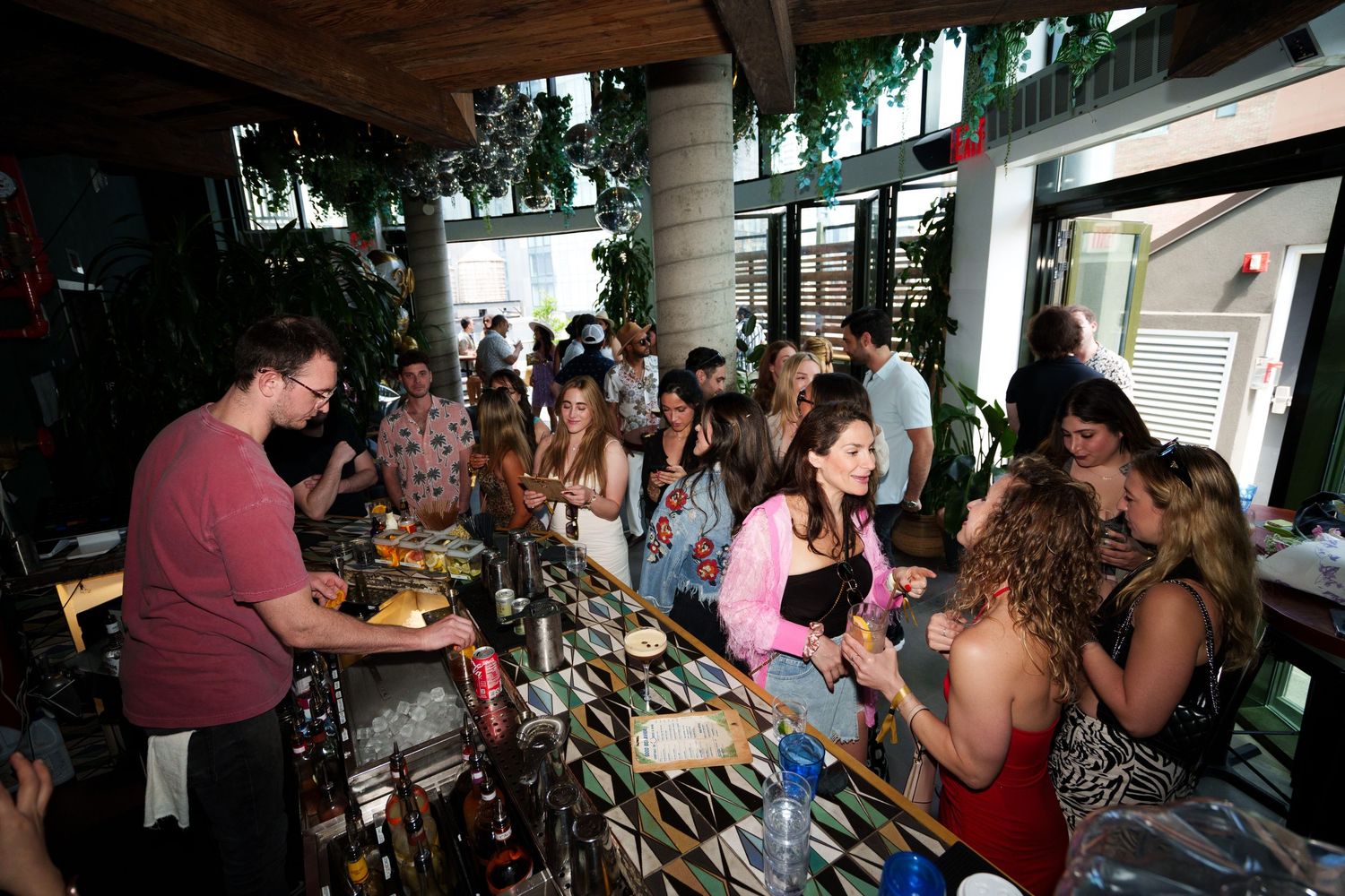 Busy bar scene with customers and bartenders serving drinks.