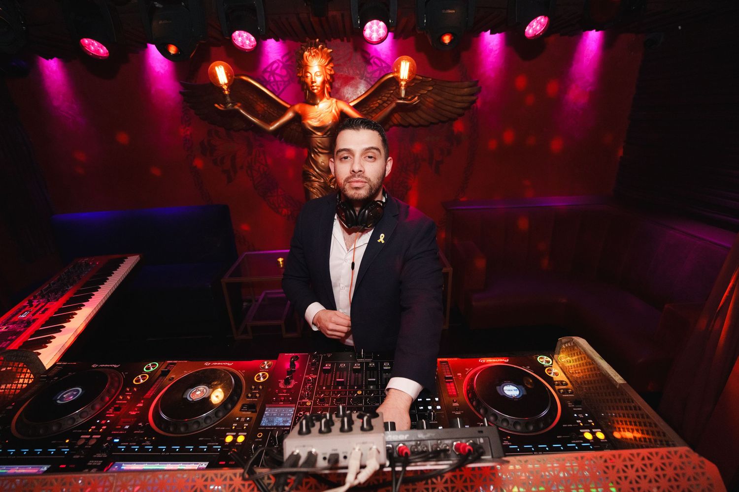 DJ performing at a nightclub setup with colorful stage lighting and professional equipment.