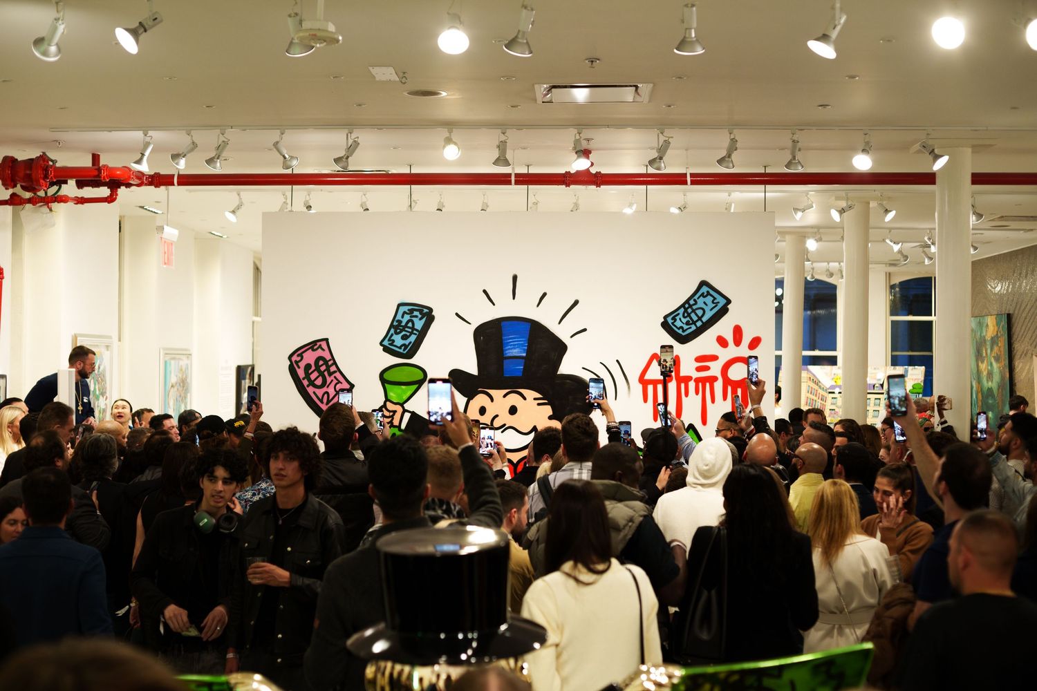 Crowded indoor event space with colorful tech-themed wall art and overhead lighting.