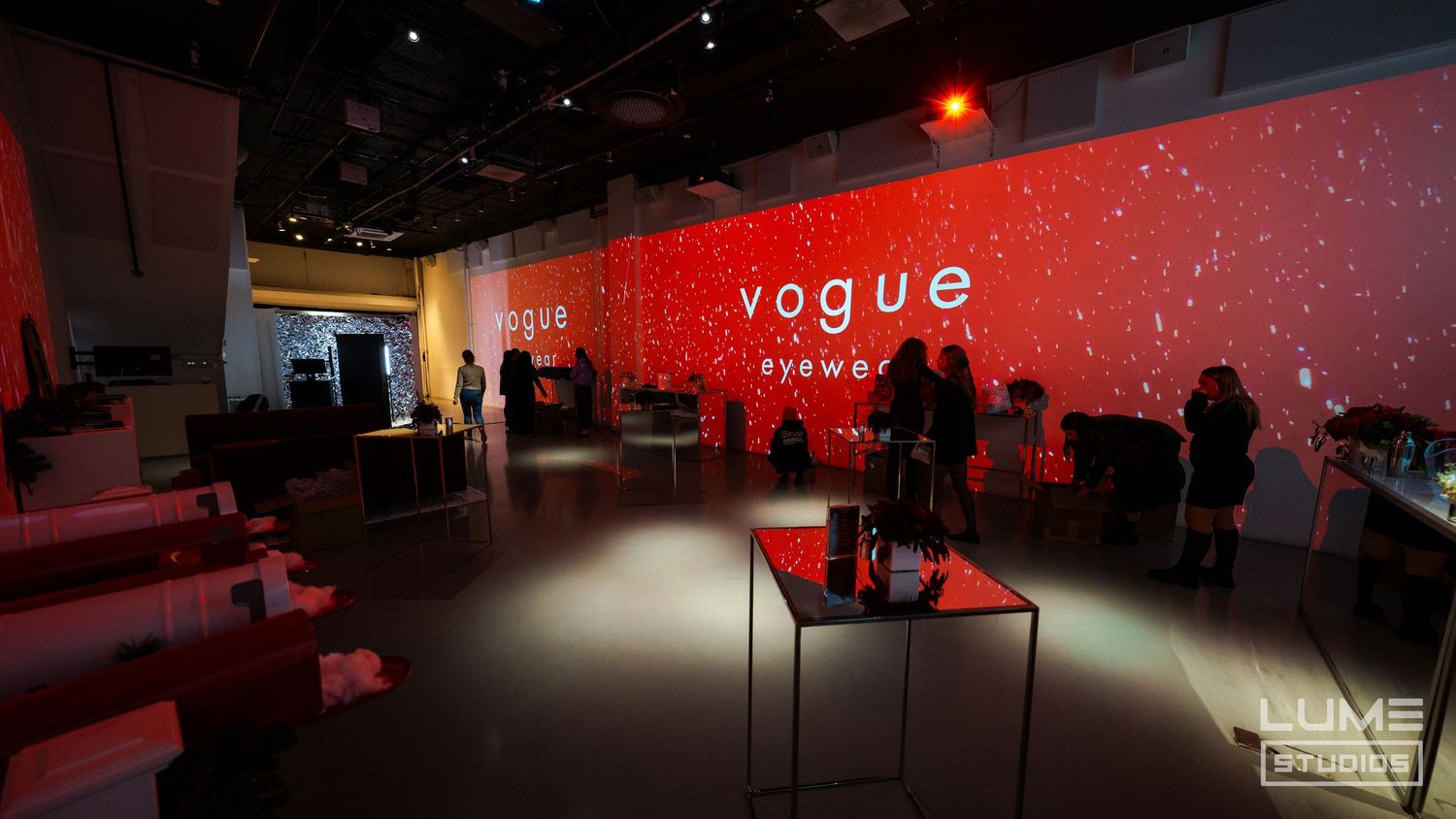 Modern event space with red illuminated walls displaying Vogue branding.
