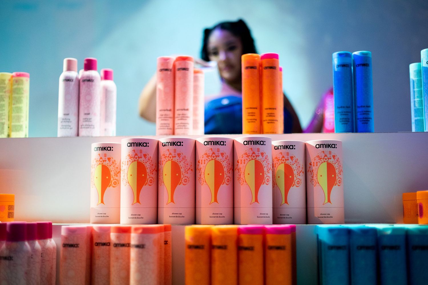 Colorful hair product bottles displayed on illuminated shelves with vibrant orange cans in focus.